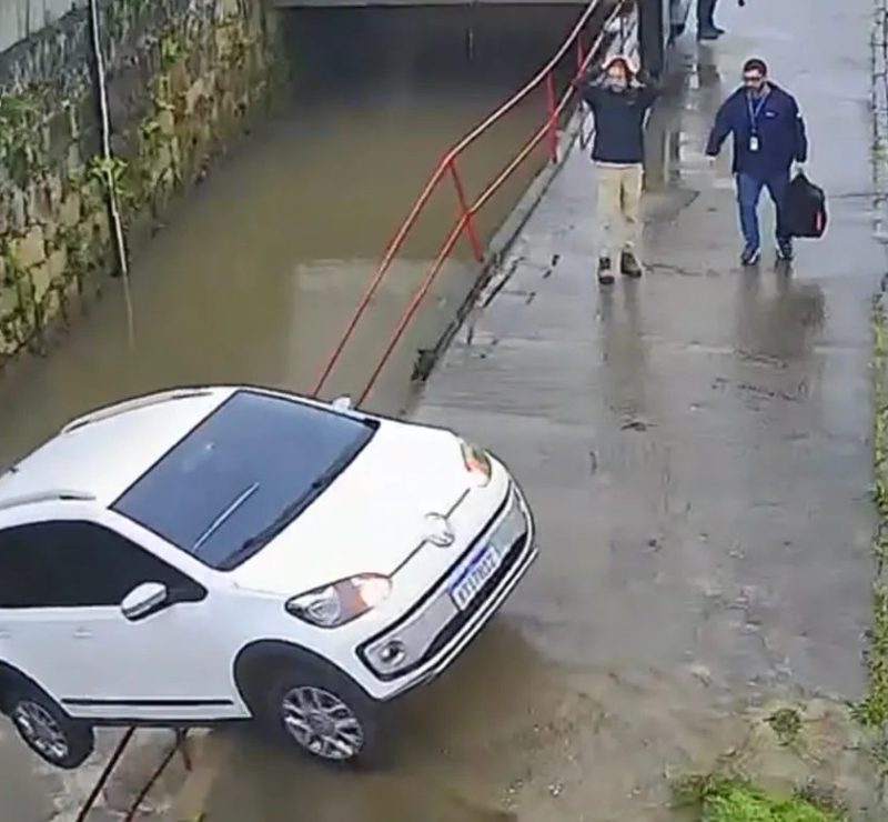 Carro sem motorista atravessa rua e cai em rio em Petrópolis; vídeo mostra reação de homem que leva as mãos à cabeça ao ver a situação