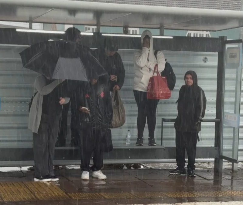 FOTO: passageiros sobem em banco para se proteger de chuvarada em parada de ônibus de Porto Alegre